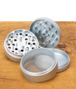 Vierteiliger EHLE Keramik Grinder in Silber offen, alle Mahlelemente und Sieb auf Holztisch zu sehen.