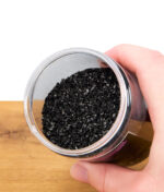 Offene Dose EHLE Aktivkohle 150 Gramm, schwarz glänzende Aktivkohle aus Kokos, Detailaufnahme mit Hand am Behälter, geeignet für Filter und Wasserpfeifen