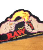 Teppich mit buntem Aufdruck von der Marke RAW im "Get Lit" Design mit Hand und Feuerzeug