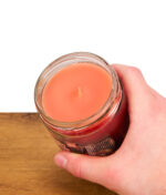 Hand hält rot orangene Duftkerze "Pumpkin and Waffles" von Smoke Odor Exterminator Duftkerzen.
