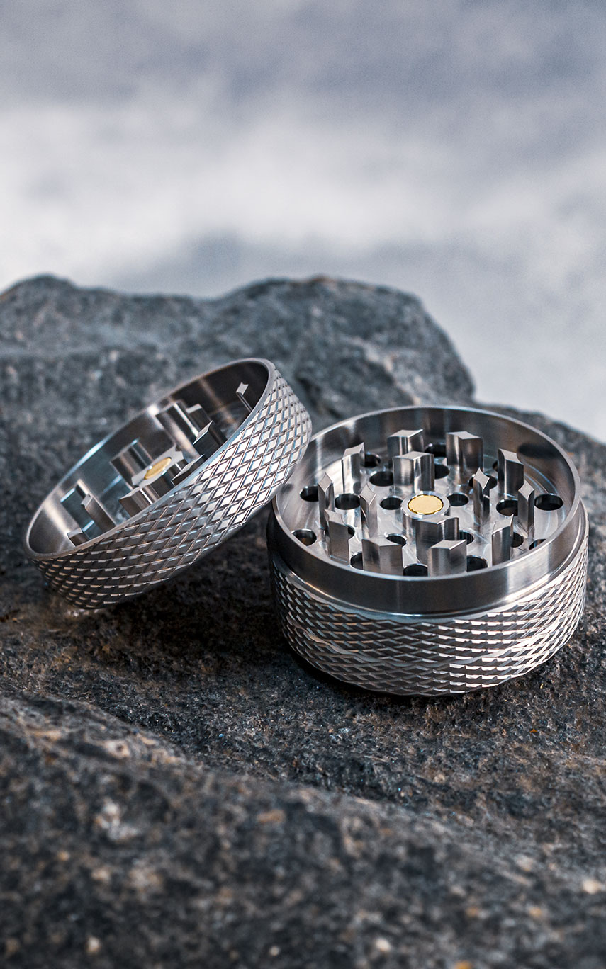 Das Bild zeigt den geöffneten GRIPO Premium Grinder 55 mit Blick auf das Mahlwerk auf einem Naturstein vor einem grauen Hintergrund platziert.