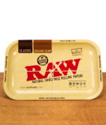 Rechteckiges RAW Rolling Tray in Beige auf Holzoberfläche, mit großem roten RAW Logo und Aufdruck „Natural Unrefined Rolling Papers“, Produktfoto von oben.