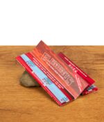 Geöffnetes Heftchen Elements Red Slow Burn Hemp Papers liegend auf einem Stein präsentiert