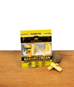 Arrangement aus King Palm Banana Cream Flavor Tips Packung und zwei einzelnen Filtern vor einem Stein