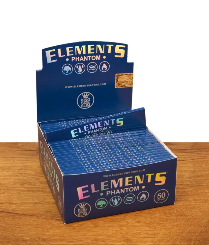 Zwei dunkelblaue Elements Phantom King Size Slim Packungen auf Holzgrund, eine stehend und eine an einen Stein gelehnt.