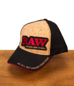 RAW Cork Panel Cap mit Front aus natürlichem Kork, schwarzem Schirm und besticktem RAW-Logo auf einer Holzoberfläche.
