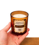 In der Hand gehaltene Smoke Odor Reserve Vanilla Tobacco Duftkerze im braunen Glas mit Vintage-Etikett.