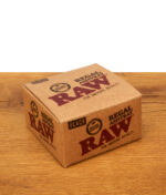 Quadratische Produktverpackung des RAW Regal Ashtray Black aus braunem Karton mit rotem Logo-Aufdruck und "Wind Resistant" Siegel.