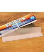 Einzelnes, transparentes Elements Ultra Thin Paper aus Reis vor der Connoisseur-Packung mit Gummiband-Verschluss auf Holz.