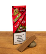 Geöffnete Kingpin Hemp Wraps Laid Back Packung neben einem braunen Hanf-Blättchen, das auf einem Stein vor Holzoptik präsentiert wird.