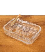 RAW Aficionado Glass Ashtray aus massivem Glas mit einem darauf abgelegten Joint in einer der Einkerbungen auf Holz.