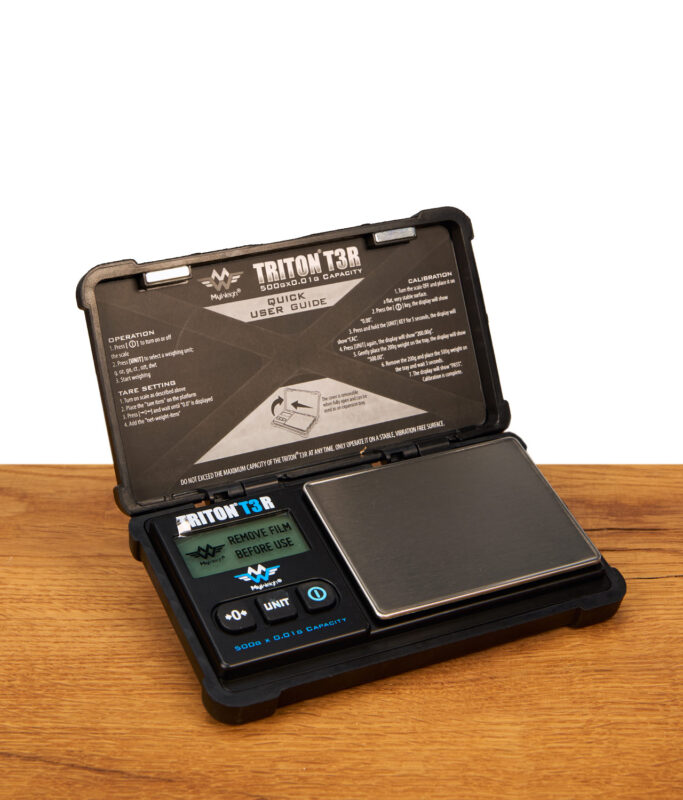 Geöffnete Triton T3R Feinwaage von MyWeigh auf Holzoberfläche mit digitalem Display und quadratischer Wiegefläche aus Edelstahl.