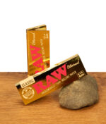 Zwei Packungen RAW Ethereal 1 1/4 Size Papers in glänzender Gold-Optik auf Holzoberfläche mit Naturstein-Akzent.