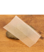 Einzelnes, ultradünnes RAW Ethereal Blättchen mit Criss-Cross-Wasserzeichen auf einem Stein zur Veranschaulichung der Transparenz.