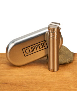 Gebürstetes Clipper Feuerzeug Metall Jetflame Silber neben einem passenden, geprägten Metalletui auf einem Holztisch.