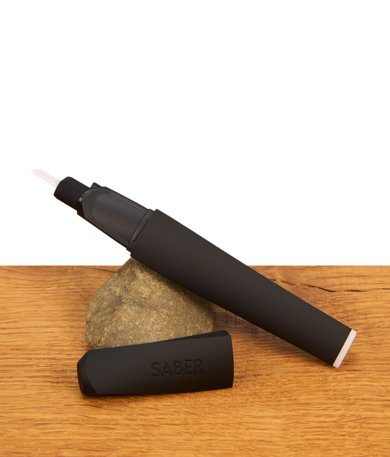 saber-hot-knife-dabbing-tool-2-jpg Focus V Saber Hot Knife mit abgenommener Schutzkappe auf einem Naturstein präsentiert, Fokus auf das schlanke, mattschwarze Design.