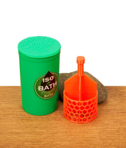 Komplettes Black Leaf Iso Bath Set: Grüner Reinigungsbehälter und orangefarbener 3D-gedruckter Korb auf einer Holzoberfläche vor einem Stein.