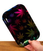Hand hält das Fire-Flow Rolling Tray Leaves Gradient Small. Schwarzes Metall-Drehtablett mit buntem Hanfblatt-Design und glänzendem Finish.