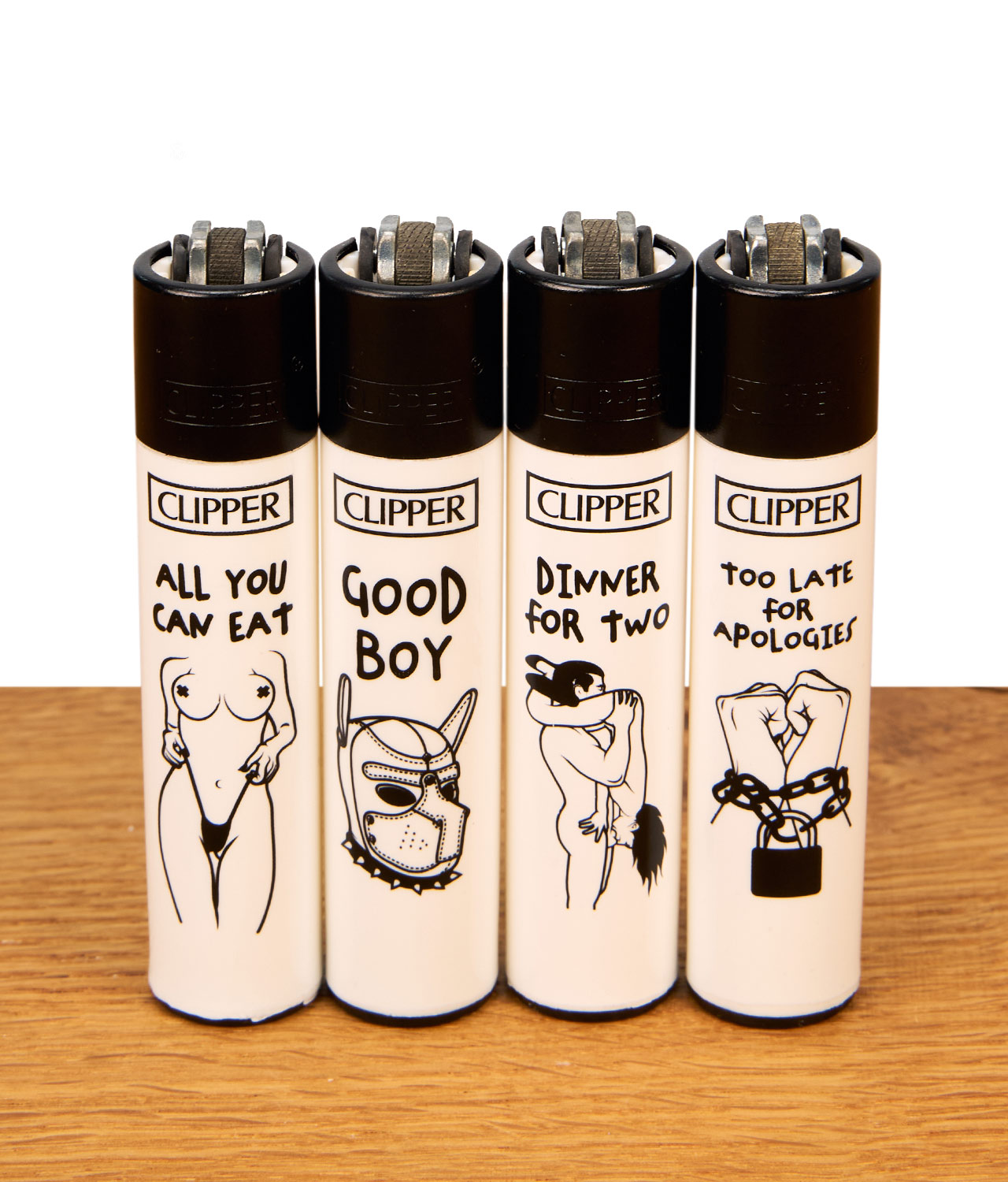 clipper-feuerzeug-ffx-adult-3-4er-serie-jpg Vier weiße Clipper Feuerzeuge der FFX Adult #3 4er Serie mit schwarzen Kappen und erotischen Strichzeichnungen auf einem Holztisch.