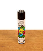 Clipper Feuerzeug Urban Flowers 100% Natural auf Holzuntergrund. Nachfüllbar, mit kleinen bunten Blüten, schwarz-weißem Graffiti und schwarzer Kappe.