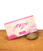 Geschlossene Purize Pink Papes 'n' Tips Packung (King Size Slim) mit Flussstein-Akzent auf Holzoberfläche. Rosa-weißes Design.