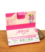 Geöffnetes Purize Pink Papes 'n' Tips Heftchen (King Size Slim) auf Holzoberfläche, gestützt durch einen Stein. Zeigt rosa Papiere und PULL-Lasche.