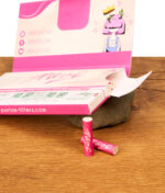 Offenes Purize Pink Papes 'n' Tips Heftchen auf Holz mit rosa Drehpapieren und zwei gerollten Purize Filtertips im Vordergrund.