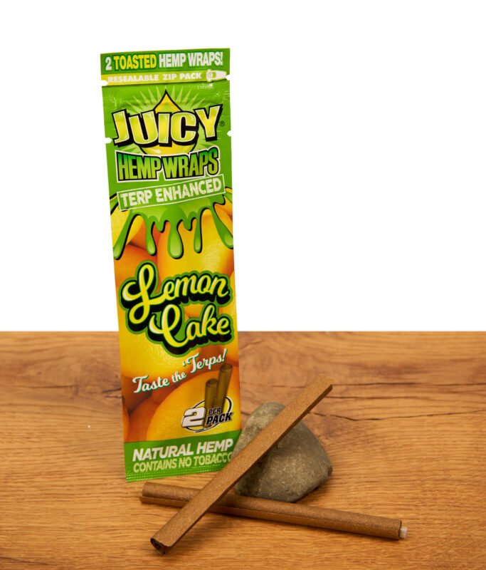 Juicy Hemp Wraps Terp Enhanced Lemon Cake 2er Pack mit zwei tabakfreien Blunts auf Holzoberfläche und Stein.