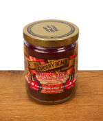 Smoke Odor Exterminator Duftkerze "Cherry Bomb" im 13oz Glas mit goldenem Metalldeckel und dekorativem Etikett auf einer Holzoberfläche.