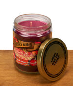 Geöffnete Cherry Bomb Duftkerze mit lilafarbenem Para-Sojawachs-Gemisch und sichtbarem Docht neben dem abgeschraubten Metalldeckel.