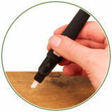 Hand hält schwarzes Dab Tool mit elektronisch aufheizender weißer Spitze für Extrakte. Auf Holz präsentiert.