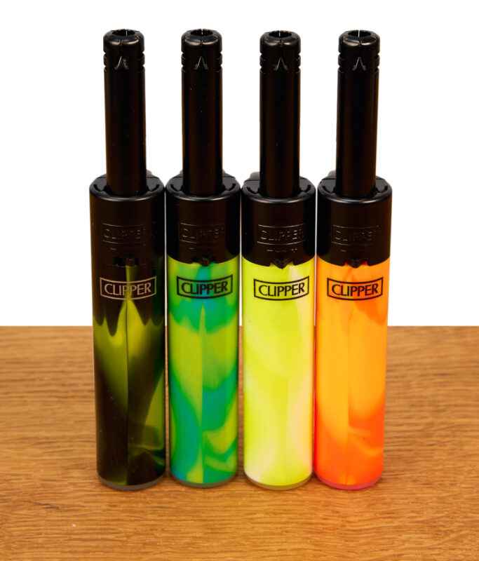 4er-Set Clipper Mini Stabfeuerzeuge Nebula Mix #4. Verschiedenfarbige, marmorierte Gehäuse mit schwarzen Metallrohren auf Holz.