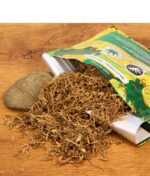 Lifestyle-Aufnahme: Der MUZA x Bunte Blüte Lemon Haze Mix liegt lose auf einer Holzoberfläche neben der geöffneten Packung und einem Stein.