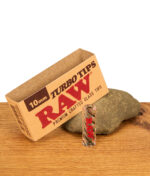 Papiermanschette der Umverpackung mit "10mm TURBO TIPS" von RAW auf Natursein angelehnt vor dem Glasfilter.
