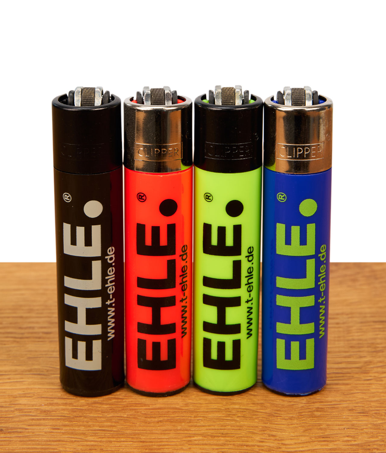 clipper-feuerzeug-ehle-4er-serie-jpg EHLE Clipper Feuerzeuge im 4er Set in Schwarz und Neonfarben mit EHLE-Logo und Web-URL auf einer Holzunterlage.