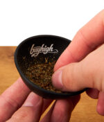 Nahaufnahme einer Hand, die Tabak und Kräuter in der schwarzen buyhigh Hash Bowl vermengt; zeigt die praktische Größe der Schale.
