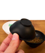 Die kompakte schwarze buyhigh Hash Bowl wird zwischen den Fingern gehalten, perfekt für die Vorbereitung von Mischungen unterwegs.