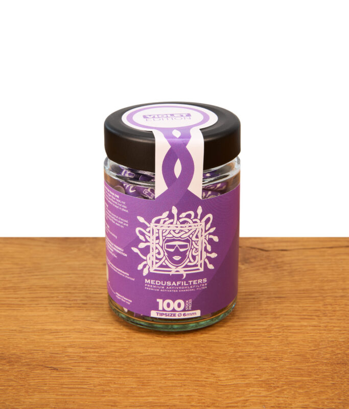 Medusafilters Violet Edition im 100er Glas. Verschlossenes Glas mit 6mm Premium Aktivkohlefiltern auf einem Holztisch.