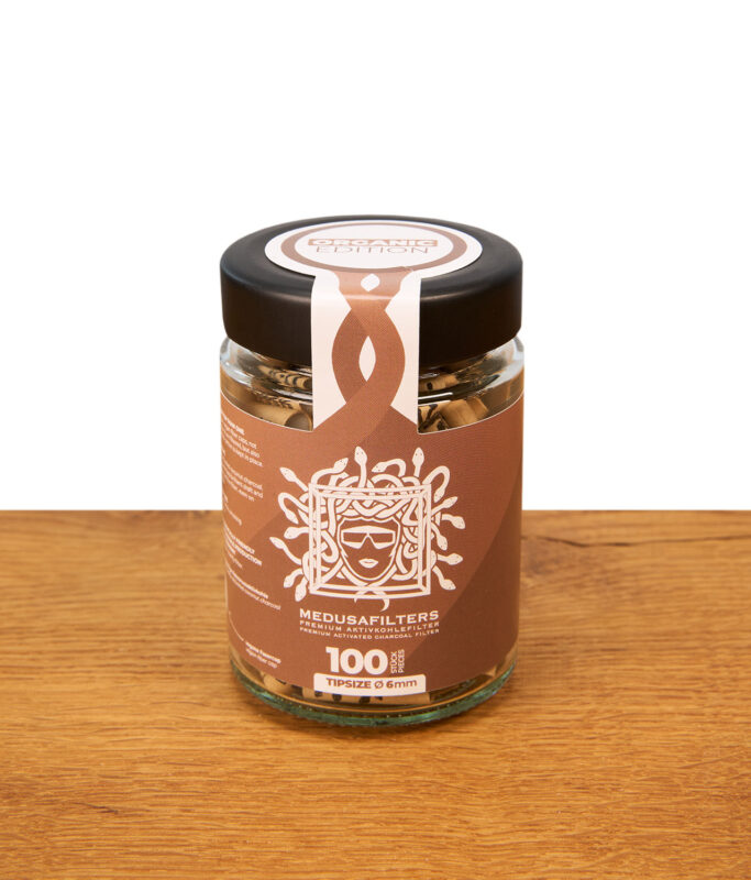 Medusafilters Organic Edition im 100er Glas. Verschlossenes Schraubglas mit 6mm Aktivkohlefiltern auf Holztisch.