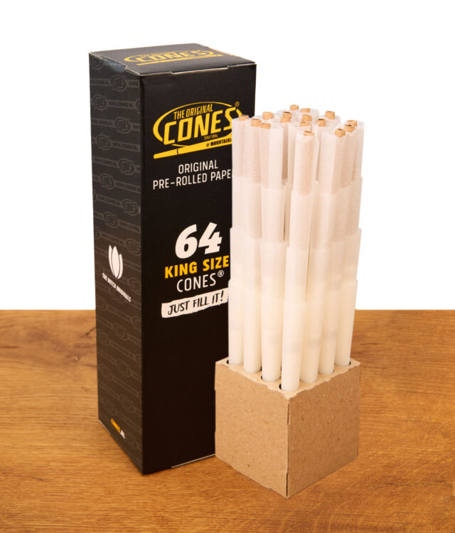 Schwarze Verpackung neben 64er Pack Cones Black King Size Prerolled mit Filtertip in Kartonhalterung.