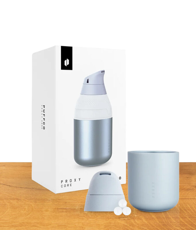 Puffco Proxy Core Accessory Haze in der Farbe Hellblau / Silber auf holz präsentiert. Mit vollem Lieferumfang vor der Verpackung.