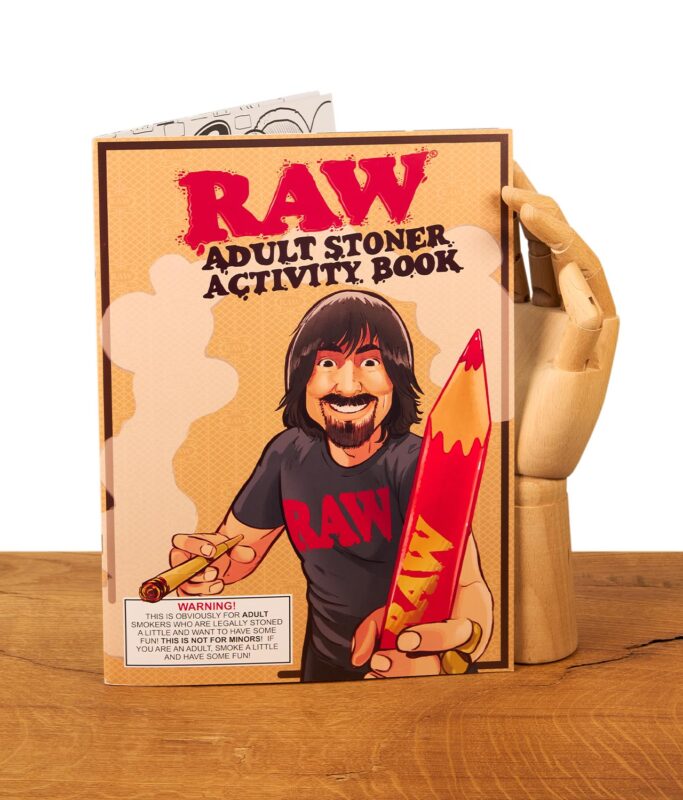 Das RAW Buch für Kiffer wird von einer hölzernen Gliederhand präsentiert, um die Größe und das Design des kreativen Activity-Hefts zu veranschaulichen.