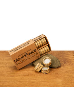 Die Moose Labs MouthPeace Micro Filter Packung liegt neben lose verteilten Filtern auf Holz, wobei der Fokus auf der „Activated Carbon Filtration“ liegt.