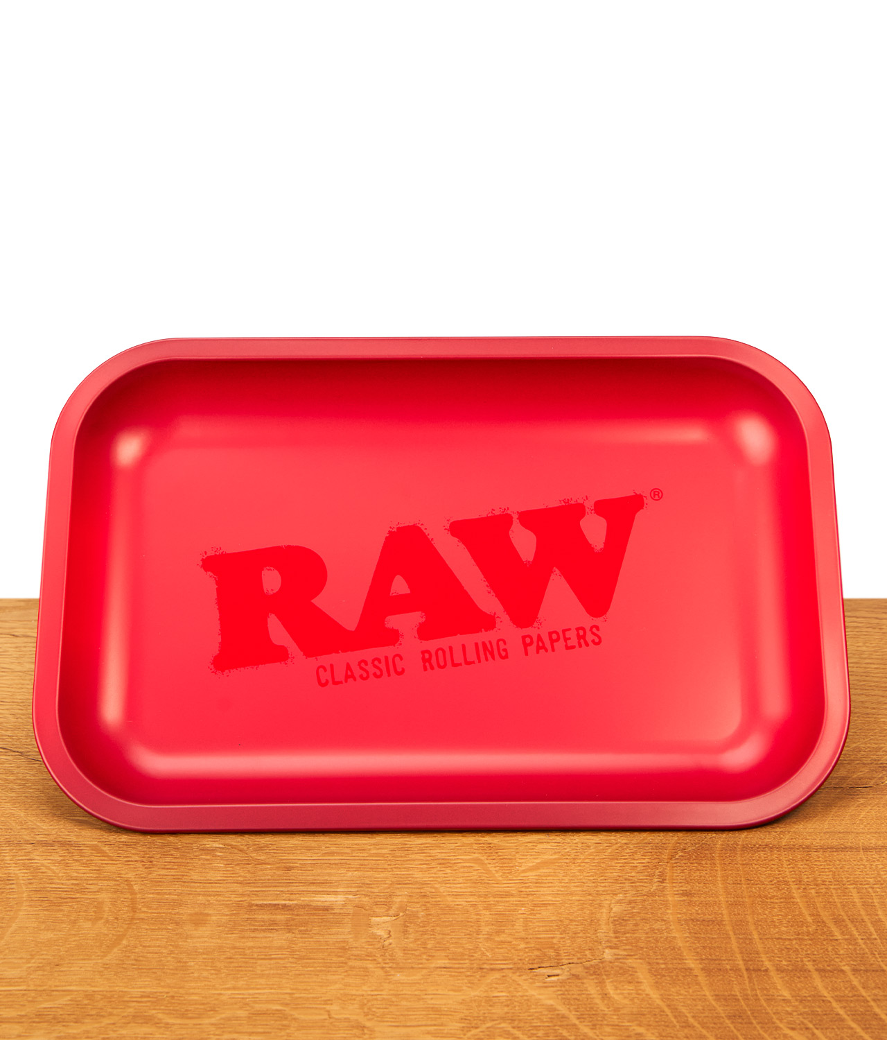 raw-red-rolling-tray-jpg Mattrote RAW Classic Rolling Tray Drehunterlage aus Metall mit dezentem, gleichfarbigem Logo auf einer Holzunterlage.