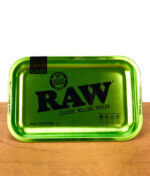 RAW Emerald Anniversary Rolling Tray in leuchtendem Grün mit schwarzem RAW-Logo und Jubiläumsaufdruck „20 Rawsome Years“ auf Holzuntergrund.
