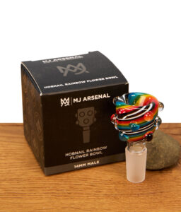 Das MJ Arsenal Hobnail Rainbow Flower Bowl (14mm Male) Köpfchen steht aufrecht neben seiner schwarzen Originalverpackung auf einem rustikalen Holzgrund.