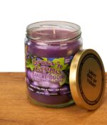 Geöffnete Smoke Odor Duftkerze Groov'n Grape gegen Tabak- und Rauchgeruch; der goldene Metalldeckel mit der Aufschrift „LIGHT ONE UP TODAY“ lehnt an dem Glas mit lilafarbenem Wachs.