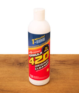 Eine Flasche des originalen Formula 420 Reinigers (12 oz / 354 ml) steht aufrecht auf einer Holzoberfläche; der ideale Express-Reiniger für Glas, Metall und Keramik.