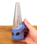 Ein Nutzer hält das saphirblaue Puffco New Peak Saphir Smart Rig in der Hand, was die kompakte Größe und das ergonomische Design veranschaulicht.