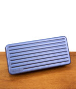 Das geschlossene Travel Case Sapphire Edition horizontal auf einem Holztisch platziert; elegantes saphirblaues Hardcase mit geprägtem Puffco-Schriftzug für den sicheren Transport unterwegs.